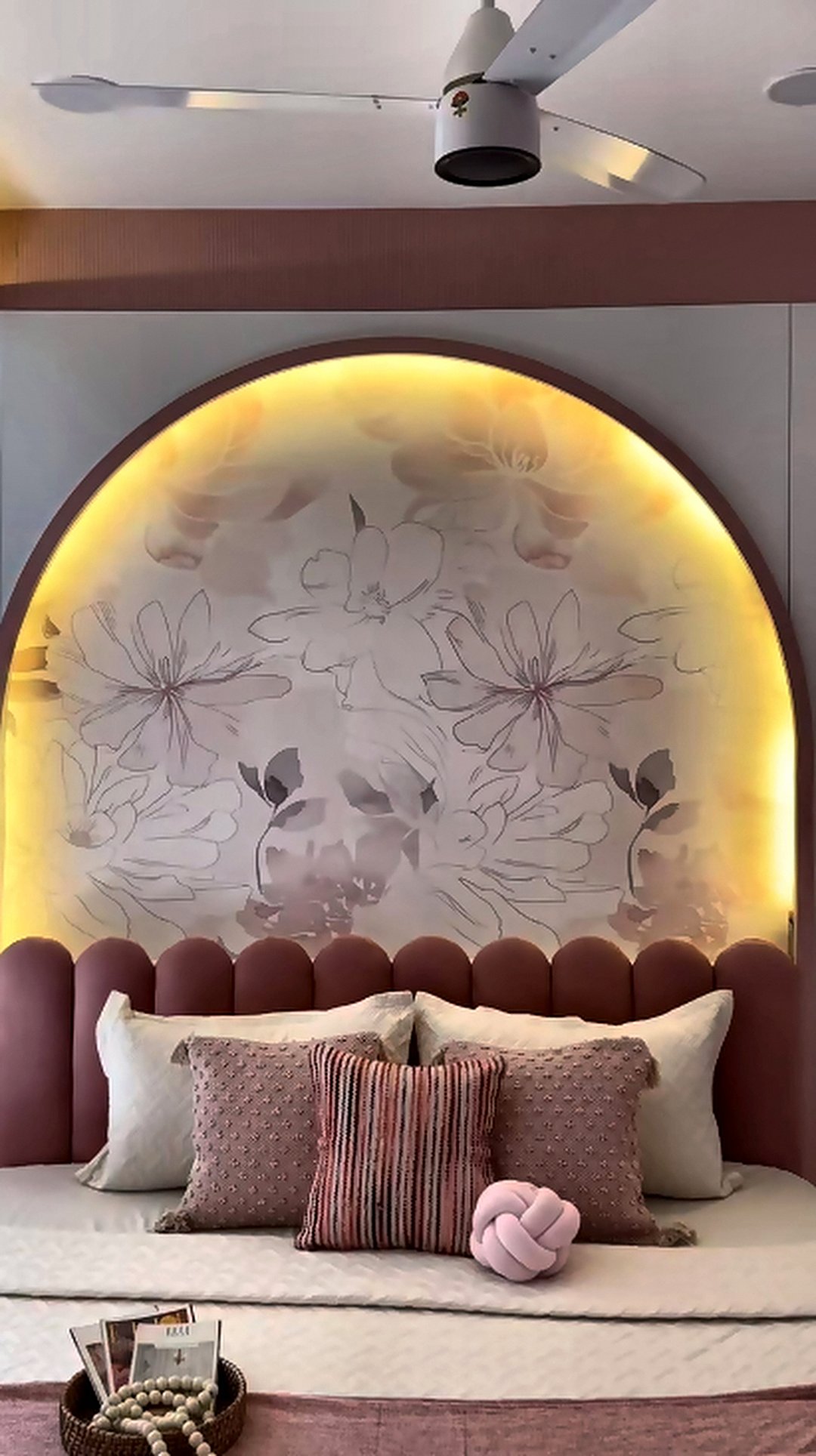 Bedroom with an arched backlit headboard and dusty rose upholstered bed in Mumbai