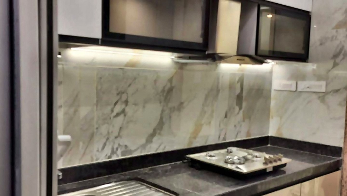 Marble backsplash and granite counter with under-cabinet lighting in a modular kitchen