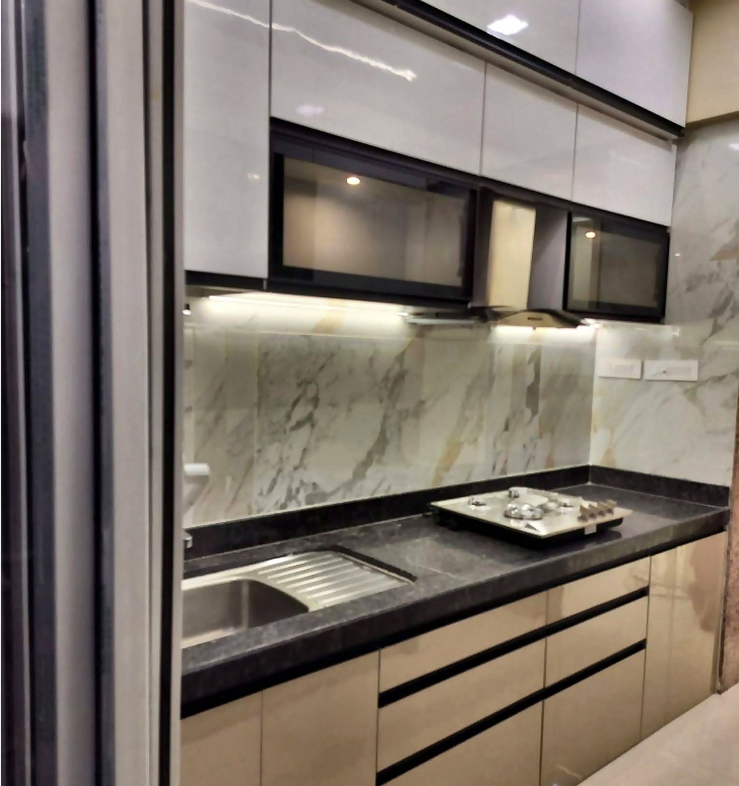 Modular kitchen in Goregaon West with glossy handleless cabinets, marble backsplash and dark granite counter