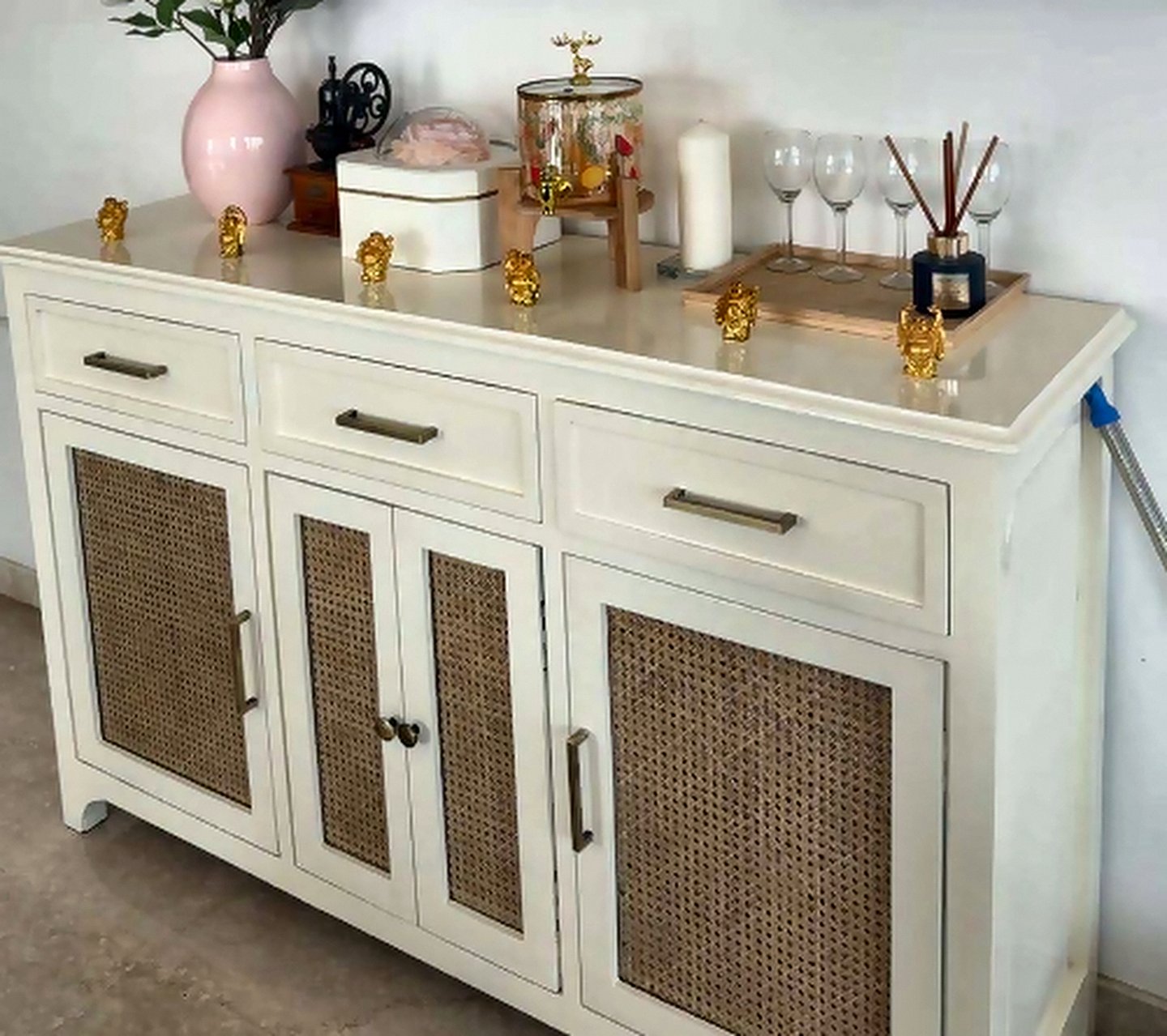 Rattan-front sideboard styled with ceramics, books and a table lamp