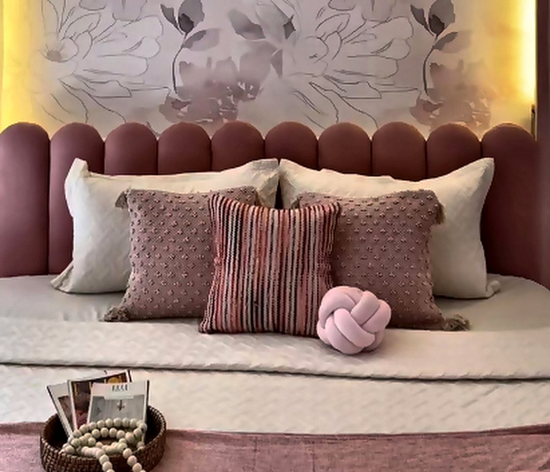 Dusty-rose upholstered bed with layered cushions